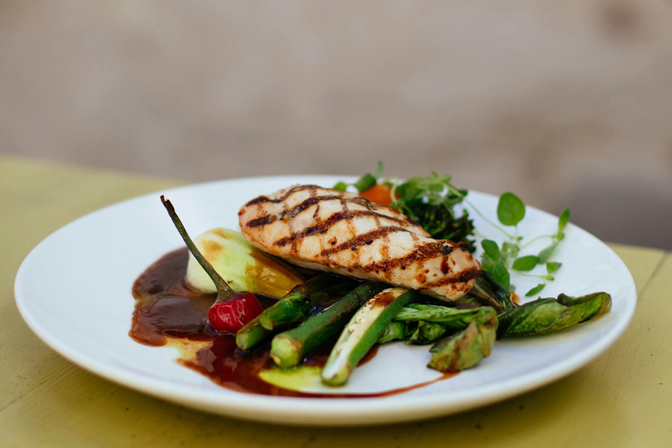 Savor a delicious grilled chicken breast paired with fresh vegetables, elegantly plated.
