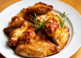 Golden-brown chicken wings garnished with fresh herbs, perfect for a tasty meal.